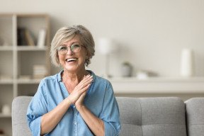 Senior woman with glasses sitting on couch and smiling