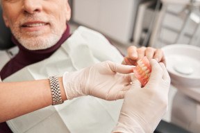 Dentist showing patient a denture in Arlington, TX