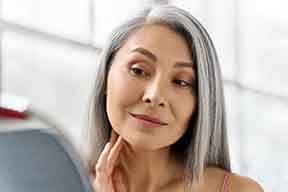 Older patient with dental implants in Arlington looking at herself in the mirror