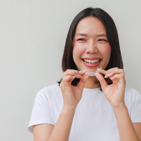 Woman smiling while holding clear aligner