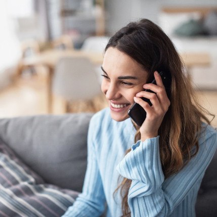 Woman smiling while talking on phone at home