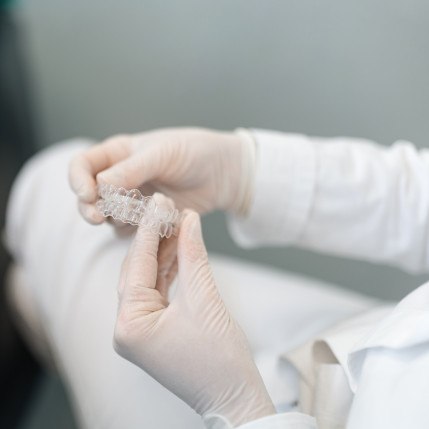 Dentist holding clear aligners with gloves